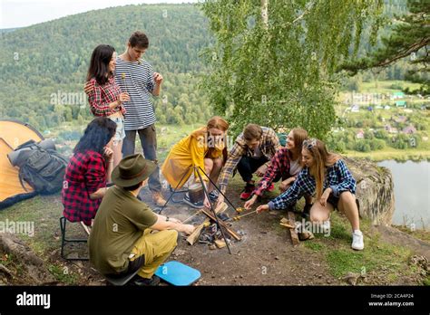 a group of young people cooking supper outdoors while resting on the ...