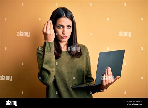 Jeune femme brunette avec des yeux bleus travaillant à l aide d un ordinateur portable sur fond