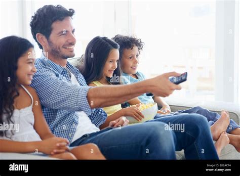 We love comedies. Shot of a family eating popcorn while sitting on a ...