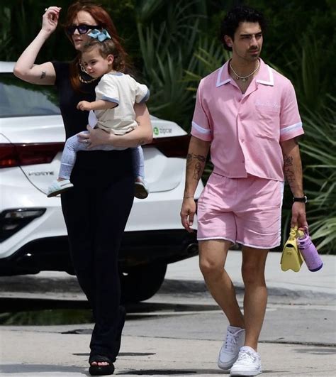 a man and woman walking down the street with a baby in their arms, both ...