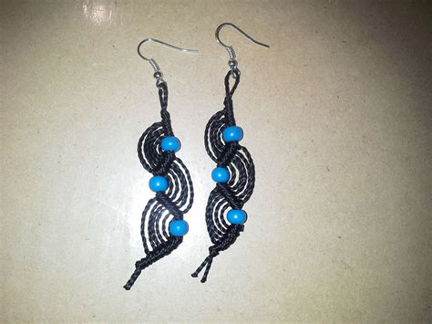 A Pair Of Black And Blue Earrings On A White Counter Top With Beads