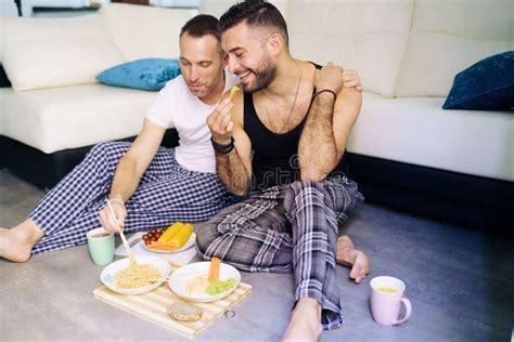 Pareja Gay Comiendo Juntos Sentados En El Piso De Su Sala De Estar Imagen De Archivo Imagen