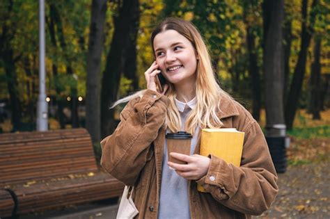 Uma Jovem Atraente Estudante Falando Ao Telefone No Parque Outono