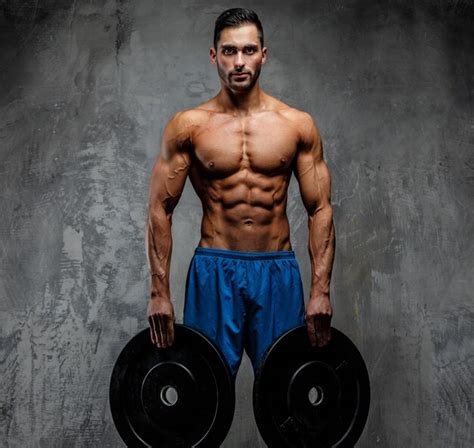 Premium Photo Muscular Man With Naked Torso Holding Weights Grey Background