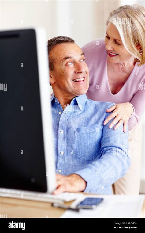 Cheerful Mature Woman Looking At Husband Working On Computer Portrait