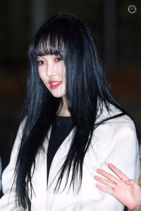 A Woman With Long Black Hair Wearing A White Jacket And Holding Her