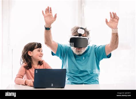 Mature Man In Modern Vr Headset Exploring Virtual Reality With Raised Arms While Sitting Near