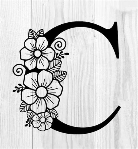 The Letter C Is Decorated With Flowers On A White Wooden Background And