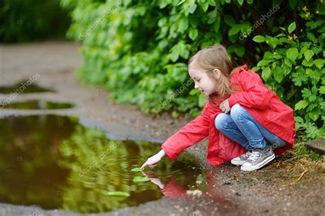 Adorable Girl Playing In Puddle Stock Photo By ©mnstudio 71448725