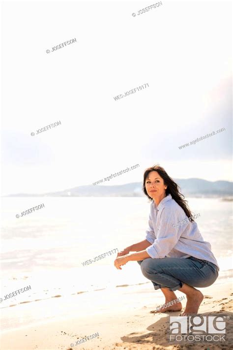 Mature Woman Spending Leisure Time Crouching On Sand At Beach Stock Photo Picture And Royalty