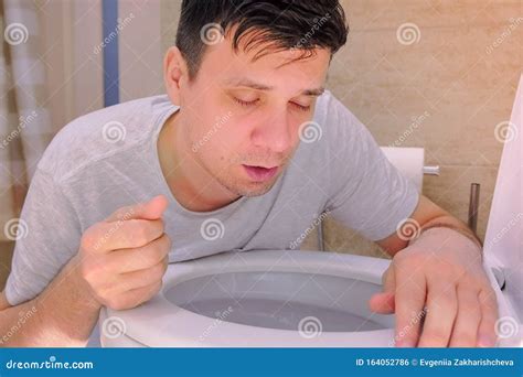 Portrait Man Vomiting In Toilet After Food Poisoning With Two Fingers