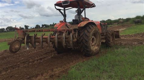 The Mu Kubota Tractor Is Plowing And Pushing The Field