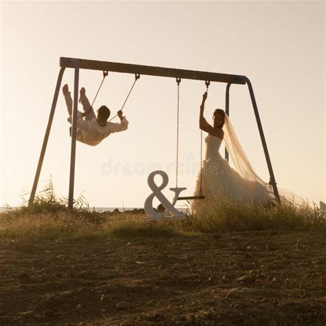 Silhouette of Young Couple Playing on Swing Set at Sunset Stock Image ...