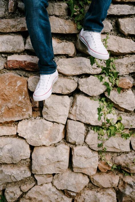 Piernas Masculinas En Jeans Y Zapatillas Al Fondo De Una Pared De