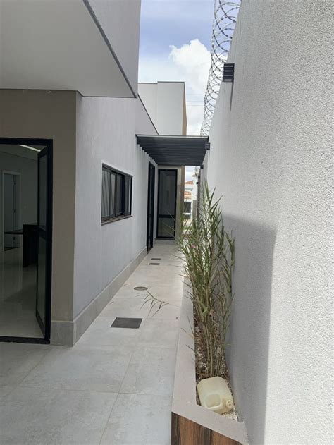 An Empty Walkway Between Two Buildings With Plants Growing In The