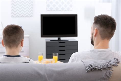 Padre e hijo viendo la televisión en casa Foto Premium