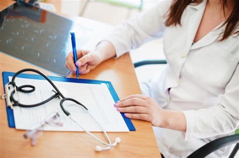 Premium Photo Midsection Of Doctor Writing On Paper At Desk