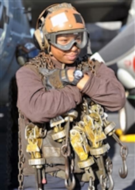 A Plane Captain Carries Tie Down Chains Across The Flight Deck