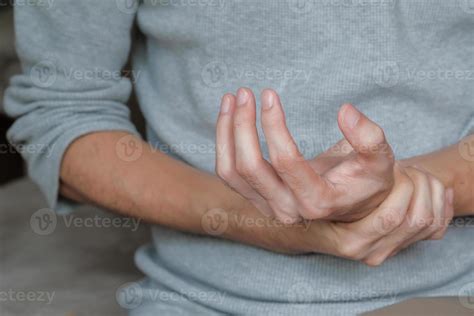 hombre asiático sosteniendo la mano con debilidad muscular