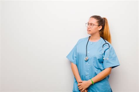 Joven enfermera latina dudando o pensando mordiéndose el labio y sintiéndose inseguro y