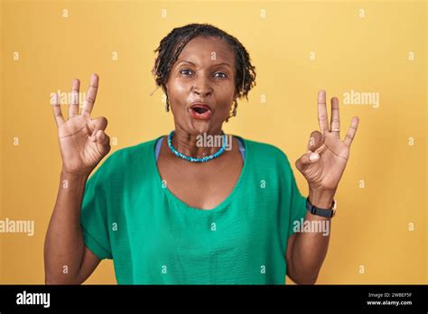 African Woman With Dreadlocks Standing Over Yellow Background Looking