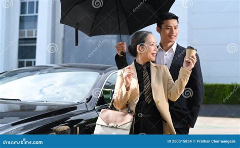 Une Femme D Affaires Mature Souriante Et Son Assistant Debout En Voiture Noire Sur Le Parking