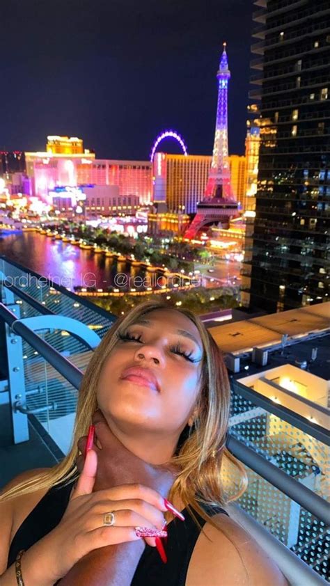 A Woman Standing On Top Of A Balcony Next To A Cityscape At Night