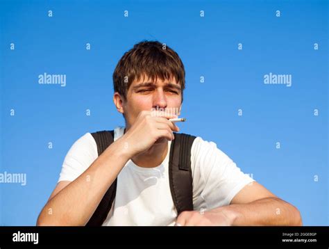 Sad Young Man smoking Cigarette on the Sky Background Stock Photo - Alamy