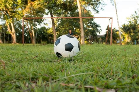 Muchacho que golpea con el pie el balón de fútbol en campo de deportes