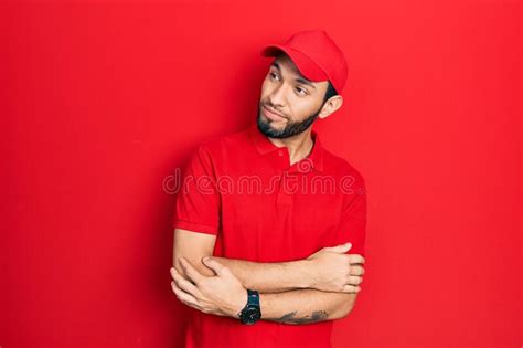 Hispanic Man With Beard Wearing Delivery Uniform And Cap Looking To The