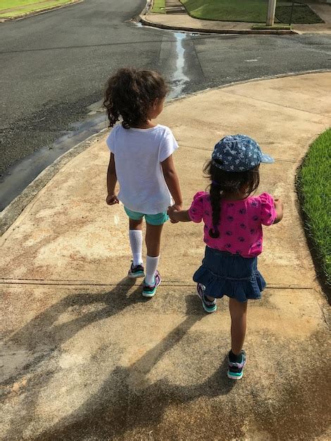 Premium Photo Rear View Of Sisters Holding Hands While Walking On