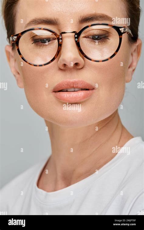 Good Looking Blonde Woman With Collected Hair And Glasses Posing On Gray Backdrop And Looking