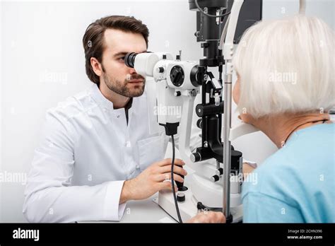 Optometrist checking vision to an old patient using a slit lamp. Eye ...