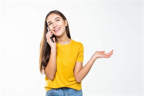 Mulher falando no celular por uma parede branca Foto Grátis