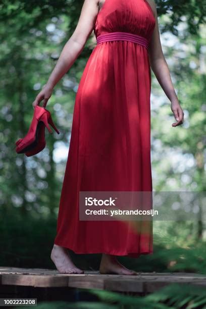 wanita berpakaian merah  kaki telanjang memegang sepatu menyeberangi