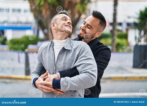men couple smiling confident hugging    street stock