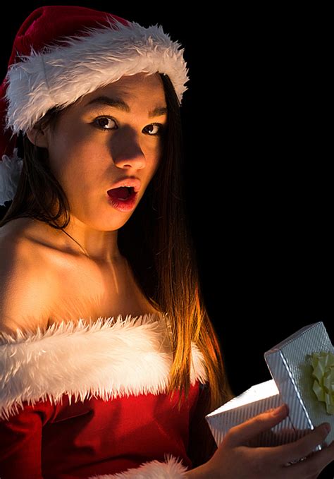 Amazed Brunette In Santa Outfit Opening A Gift