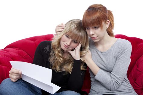 De Jonge Mooie Blonde En Rode Haired Meisjes Op Rode Bank Zijn Droevige B Stock Afbeelding