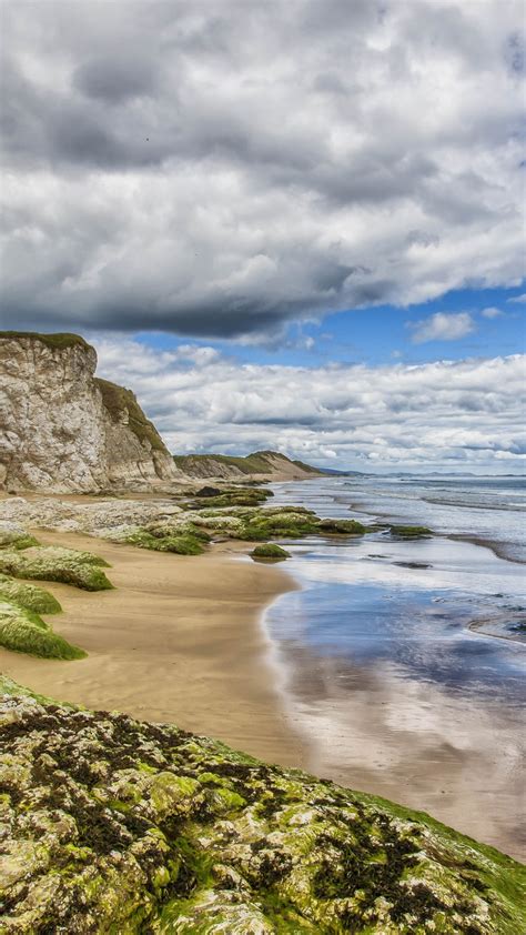 Greenery White Rocks Ocean Waves Beach Sand Under White Clouds Blue Sky