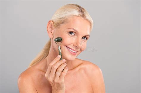 Photo Of Positive Happy Senior Lady Nude Shoulders Doing Face Procedures Isolated Grey Color