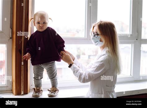 Petite fille blonde bébé debout sur le rebord de la fenêtre près des enfants médecin portant l