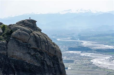 Homem e mulher em pé na beira de uma montanha observando a vista