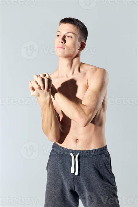 A Naked Athlete In Shorts On A Light Background Gestures With His Hands