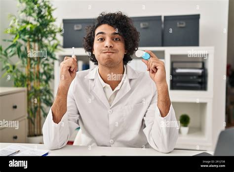 Hispanic Man With Curly Hair Holding Contact Lenses Puffing Cheeks With