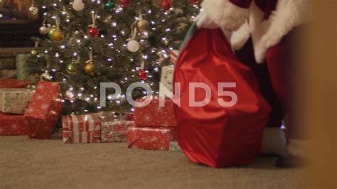 Santa Putting Presents Under A Christmas Tree