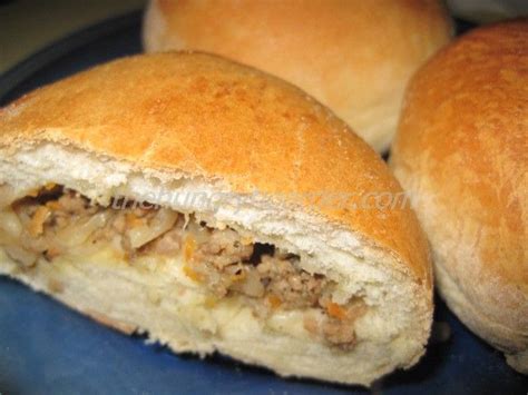 Two Rolls With Meat And Cheese Are On A Blue Plate