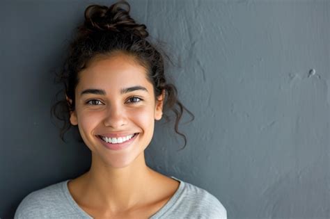 Sonriente Joven Latina Con Fondo De Pared Gris Foto Premium
