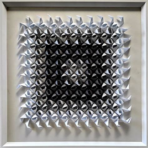 an abstract art piece made out of folded origami paper in a white frame