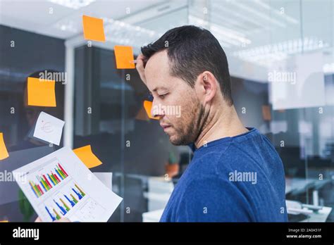Mature Businessman Writing On Sticky Notes At Glass Pane In Office Stock Photo Alamy