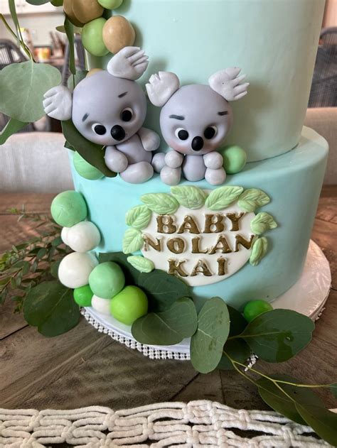 There Is A Cake Decorated With Two Koalas On The Top And Green Leaves